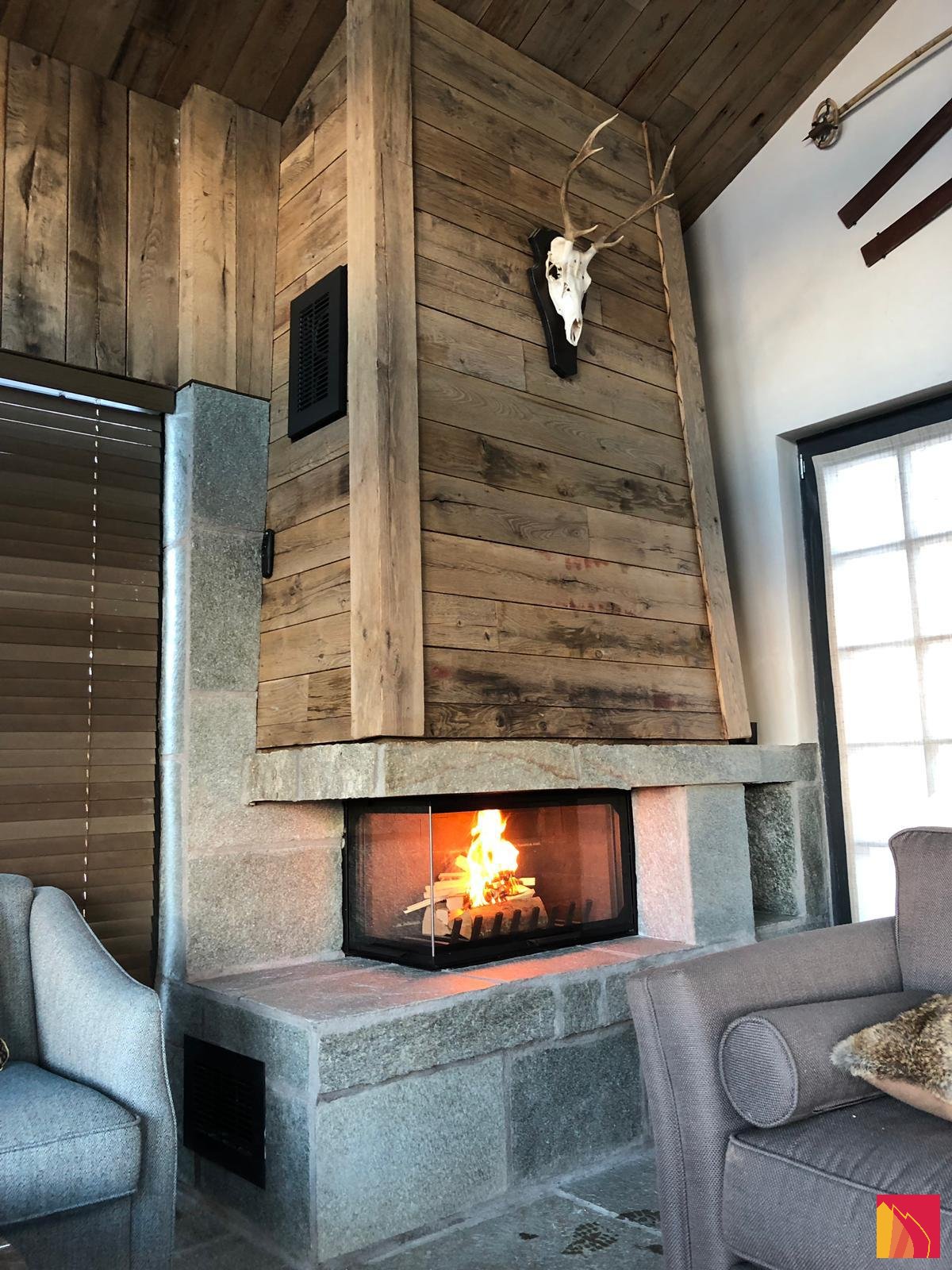 Side-glass fireplace with a stone base and a wooden covering - Carron-Lugon